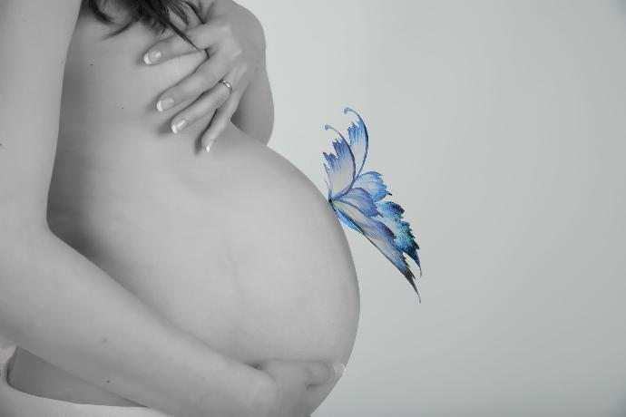 papillon posé sur le ventre d'une femme enceinte